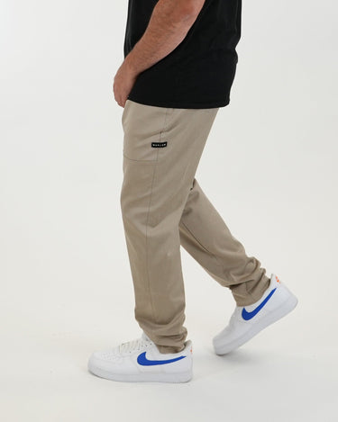 Tall man wearing beige pants with black T-shirt and white sneakers