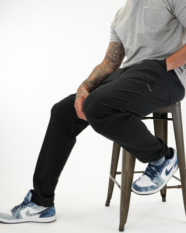 Tall man wearing black pants with grey T-shirt and blue-and-white sneakers