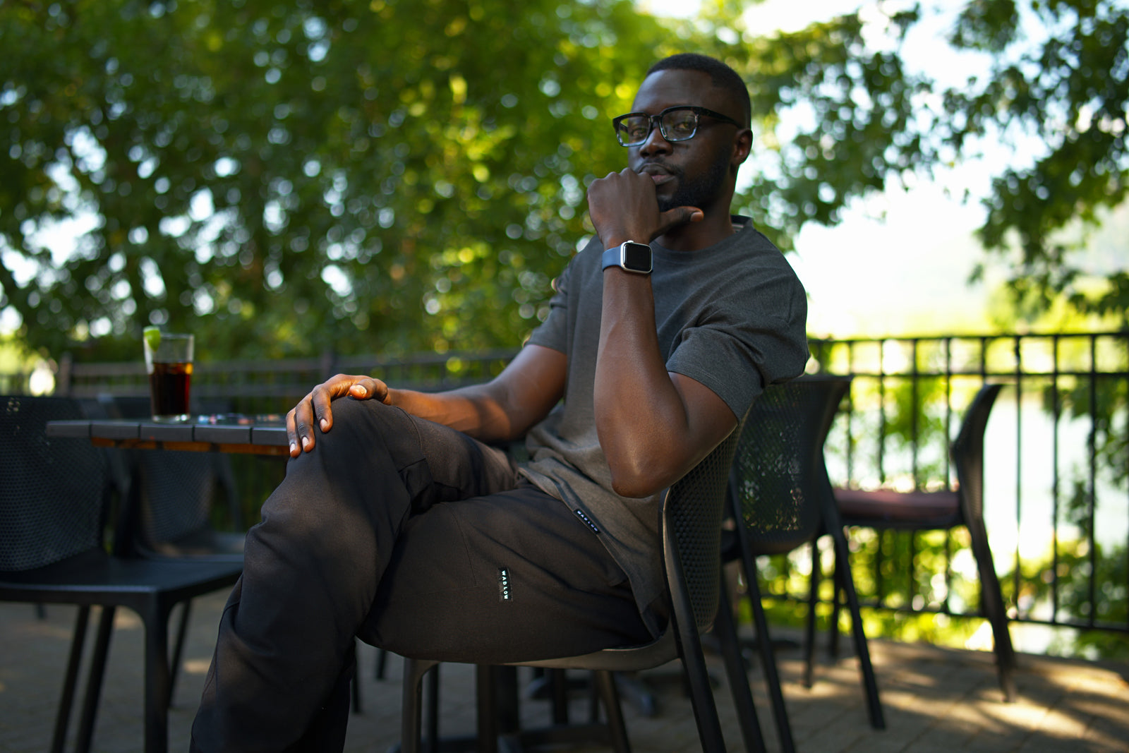 Tall man wearing black Wadlow Tall Set Pants and a dark grey Pon'tee, sitting outdoors.