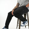 Tall man wearing black pants with grey T-shirt and blue-and-white sneakers